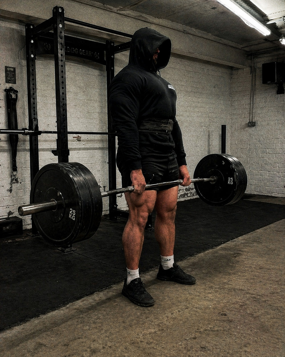 Hooded GYMHOOD lifter at the top of a heavy deadlift lockout in a real UK gym